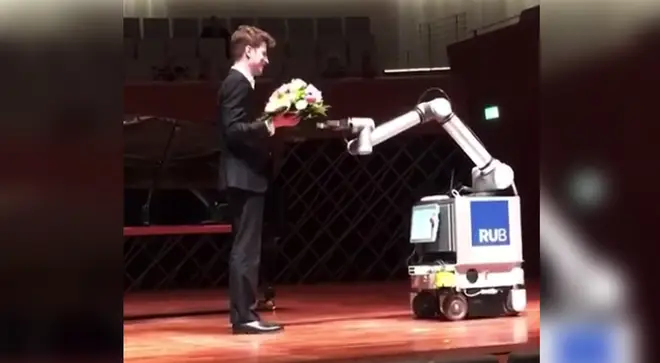 Pianist receives flowers from a robot after his performance
