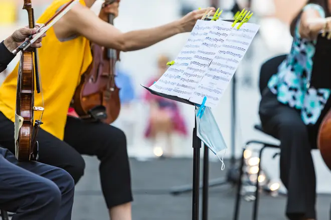 A face mask hangs from the music stand of a musician playing at an open-air concert in Madrid