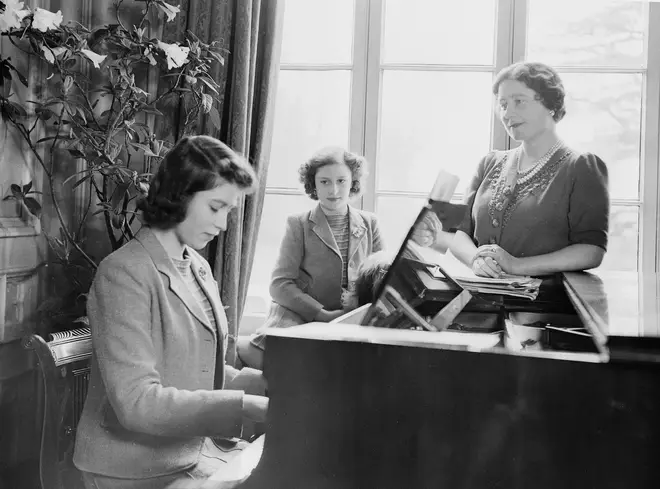 Princess Elizabeth plays the piano as Queen Elizabeth and Princess Margaret look on at the Royal Lodge in Windsor Castle