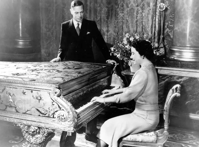 George VI watches as Queen Elizabeth (The Queen Mother) plays piano