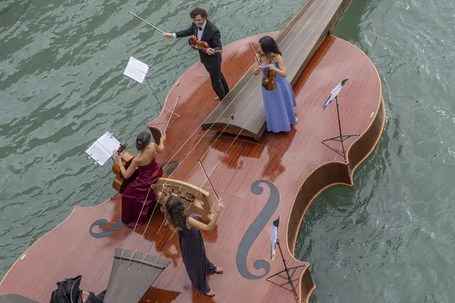 Musicians play on board a violin-shaped boat in Venice, Italy