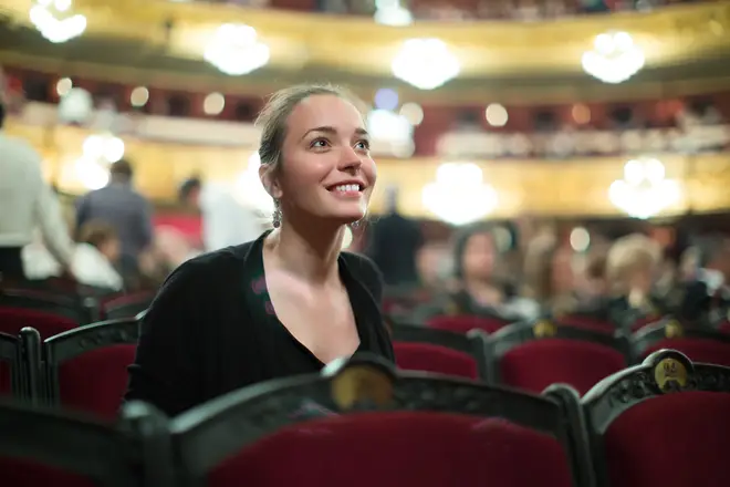 Portrait of excited young woman in auditorium of theatre