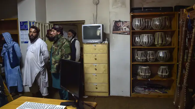 Taliban fighters standing in a room where instruments are kept at the Afghanistan National Institute of Music in Kabul