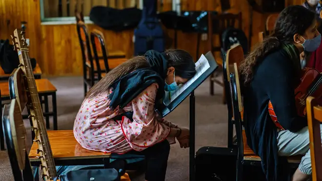 Anita, rests her head on her music notes during rehearsal for the Zohra Orchestra at Afghanistan National Institute of Music, in Kabul