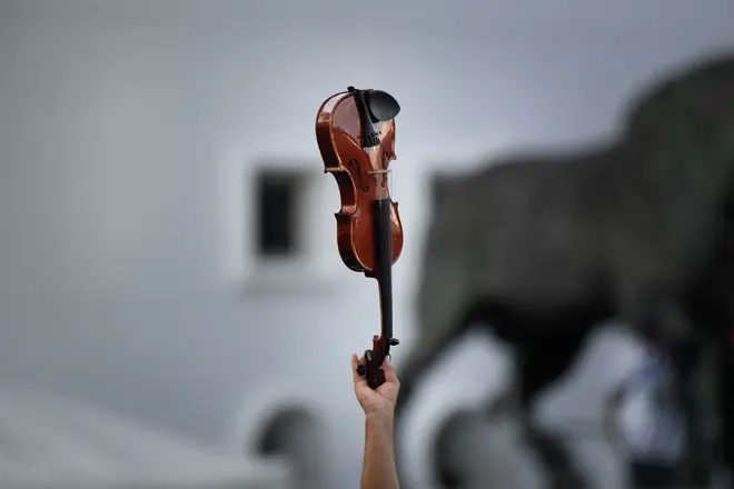 A member of the orchestra raises his violin during the world record attempt