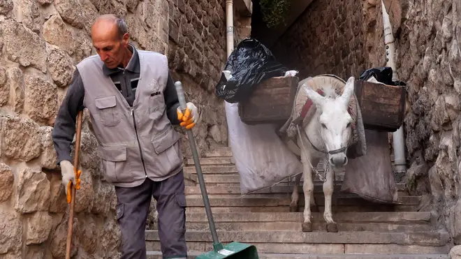A municipal worker guides a rubbish-carrying donkey through the narrow streets of the old town of Mardin