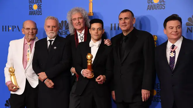 Rami Malek celebrates his win with members of Queen