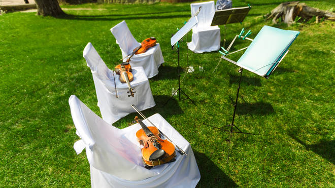 A wedding string quartet set up in direct sunlight, with instruments left on seats