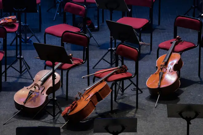 Cellos rest against empty chairs.