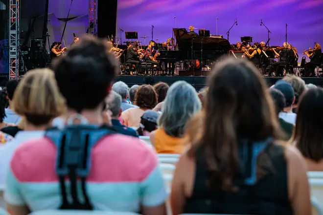 Two individuals wearing the M:NI haptic suits enjoy an orchestral concert at the Lincoln Center