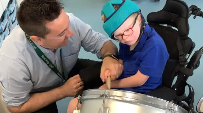 Jason Redhead teaches a child at Red Kite Special Academy how to play drums