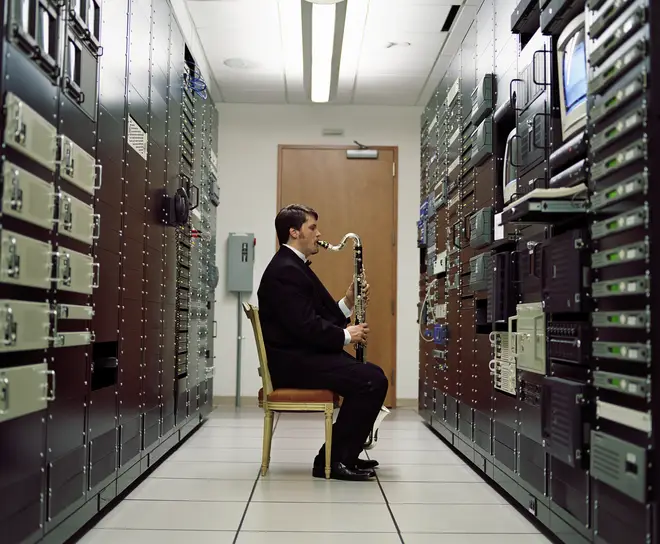 Man playing bass clarinet in a server room